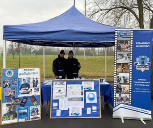 Dwie policjantki pozują do zdjęcia przy stoisku promującym zawód policjanta.