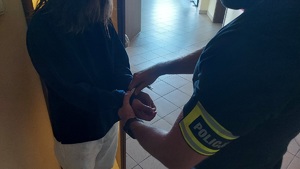 Policjant zakłada kobiecie kajdanki.