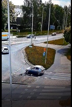 Ulica w mieście, samochód uderzył w rowerzystkę, która leży przed samochodem.