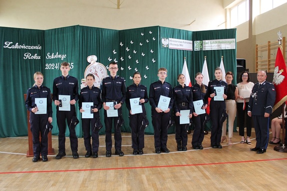 Grupowe zdjęcie uczniów, którzy otrzymali pagony, dwóch nauczycielek i policjanta.
