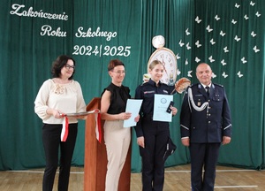 Do zdjęcia pozuje uczennica w mundurze, policjant i dwie nauczycielki.