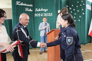 Komendant ściska uczennicy rękę gratulując.