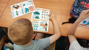 Dzieci oglądają ulotki dotyczące zachowania i bezpiecznego wypoczynku.