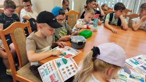 Dzieci oglądają ulotki dotyczące zachowania i bezpiecznego wypoczynku.