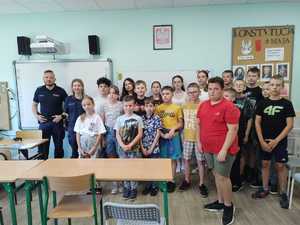 Klasa szkolna, uczniowie i policjanci pozują razem do grupowego zdjęcia.