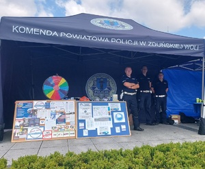 Namiot z napisem Komenda Powiatowa Policji w Zduńskiej Woli. Pod namiotem, przy stoisku stoi policjant.