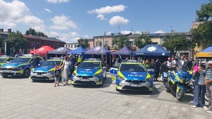 Na placu są ustawione w szyku policyjne radiowozy i motocykle.