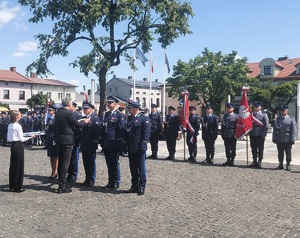 Policjanci stoją w rzędzie na środku placu. mają wręczane medale.