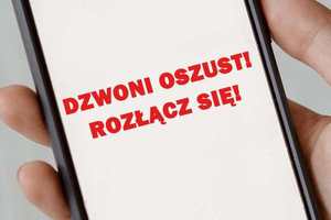 Telefon trzymany w dłoni, na którego ekranie widniej komunikat - dzwoni oszust rozłącz się.