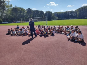Spotkanie policjantki z dziećmi biorącymi udział w sportowych półkoloniach.
