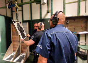 Policjant ma założone nauszniki, tak samo instruktorzy strzelania, którzy zliczają punkty z tarczy.