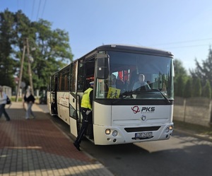 Policjat wsiada do autobusu.