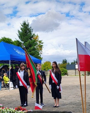 Szkolny poczet sztandarowy oddaje hołd pod pomnikiem.
