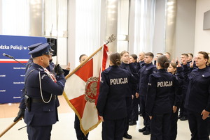 Uroczystość ślubowania, policjanci mają podniesione do góry dwa palce i składają przysięgę na sztandar.