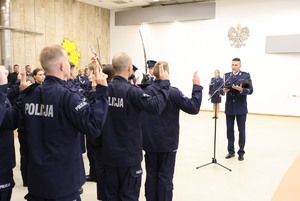 Policjanci składają rotę ślubowania, na wprost nich stoi policjant.