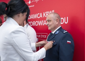 Kobieta wpina policjantowi do munduru medal.