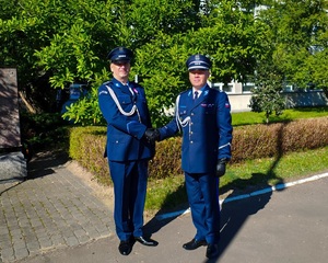 Dwóch policjantów pozuje do zdjęcia, podają sobie dłonie w uścisku.