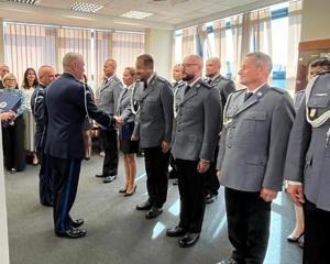 W dwuszeregu stoją mianowani policjanci, komendant podaje im rękę i akty mianowania, gratuluje im.