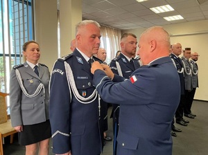 Policjant wpina w klapę munduru drugiego policjanta medal.