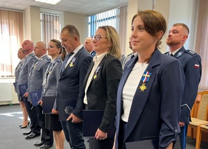 Osoby z przypiętymi medalami stoją w dwuszeregu.