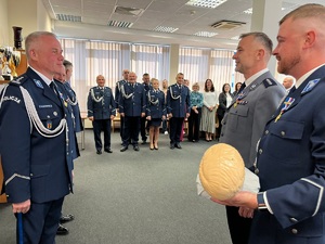Dwaj policjanci wręczają komendantowi fantoma do ćwiczeń.