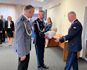 Komendant przyjmuje od policjantów fantoma, bierze go do rąk.