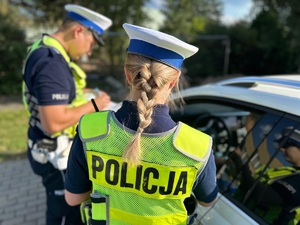 Dwoje policjantów kontroluje kierującego samochodem.