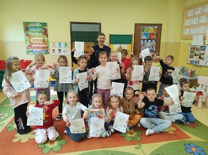 Grupowe zdjęcie dzieci i policjantki. Wszyscy pozują do zdjęcia.