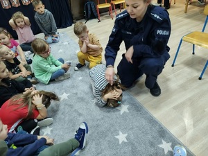 Policjantka z przedszkolakiem pokazująca pozycję żółwia, która chroni przed atakiem psa.