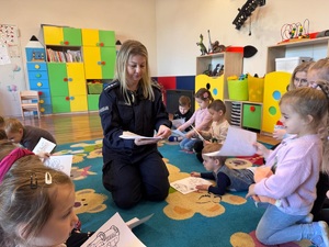 Policjantka rozdaje dzieciom kolorowanki.