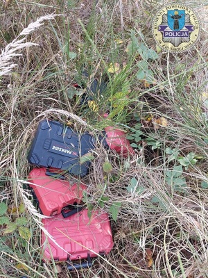 Na trawie, w krzakach leżą skrzynki z elektronarzędziami.