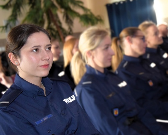 Na krzesełkach, jako publiczność w sali, siedzą umundurowane policjantki.