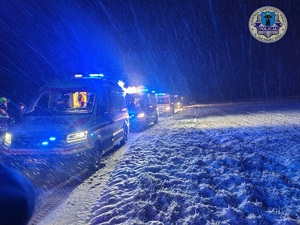 Noc, wzdłuż drogi stoją pojazdy służb ratunkowych.