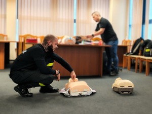 Aula w komendzie. Dwaj strażacy pokazują fantomy, na których ćwiczy się resuscytację krążeniowo-oddechową.