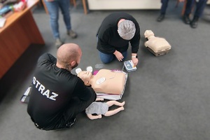 Kobieta ćwiczy na fantomie pierwszą pomoc, obok niej strażak instruktor.