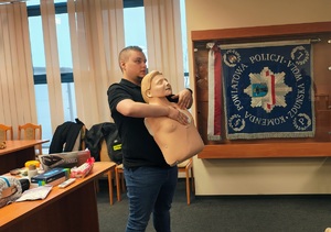 Strażak trzyma w rękach fantoma, pokazuje go.