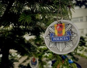 Gałązki choinki, na której zawieszony jest element odblaskowy z logo jednostki policji.
