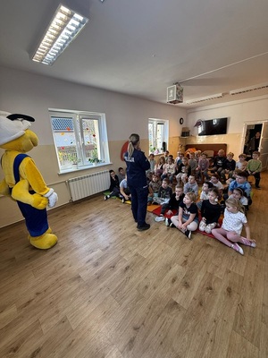 Policjantka na spotkaniu z dziećmi, które siedzą na podłodze.