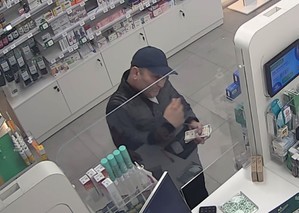 Przy kasie w aptece stoi mężczyzna. Trzyma w rękach pieniądze.