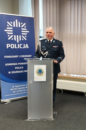 Policjant przy mównicy.