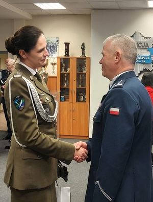 Żołnierka składa komendantowi życzenia. Podają sobie dłonie.