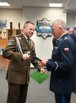 Żołnierz składa komendantowi życzenia. Podają sobie dłonie.