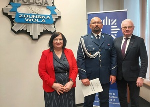 Do zdjęcia pozuje policjant oraz goście uroczystości.