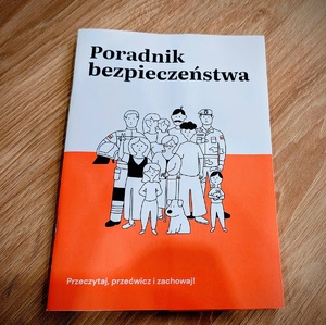 Na stole leży książeczka "Poradnik bezpieczeństwa".