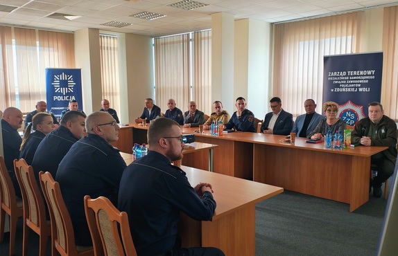 Aula komendy. Za stołami siedzą policjanci i goście odprawy.
