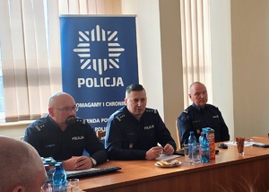 Trzech komendantów siedzi za stołem.