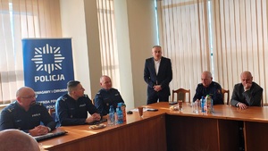 Aula komendy. Za stołami siedzą policjanci i goście odprawy. Jeden z gości wstał, mówi do zebranych.