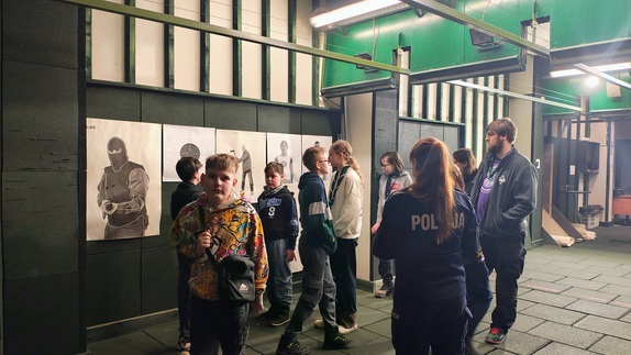 Policjantka pokazuje młodzieży strzelnicę.