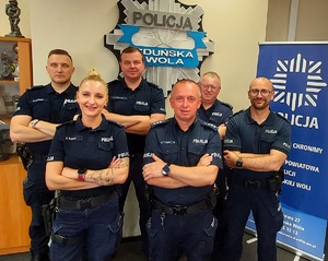 W pomieszczeniu, pod ścianą stoi umundurowanych 5 policjantów i 1 policjantka, mają ręce założone na ramionach, pozują do zdjęcia.