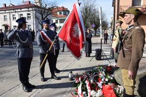 Poczet sztandarowy składa hołd przed pomnikiem.